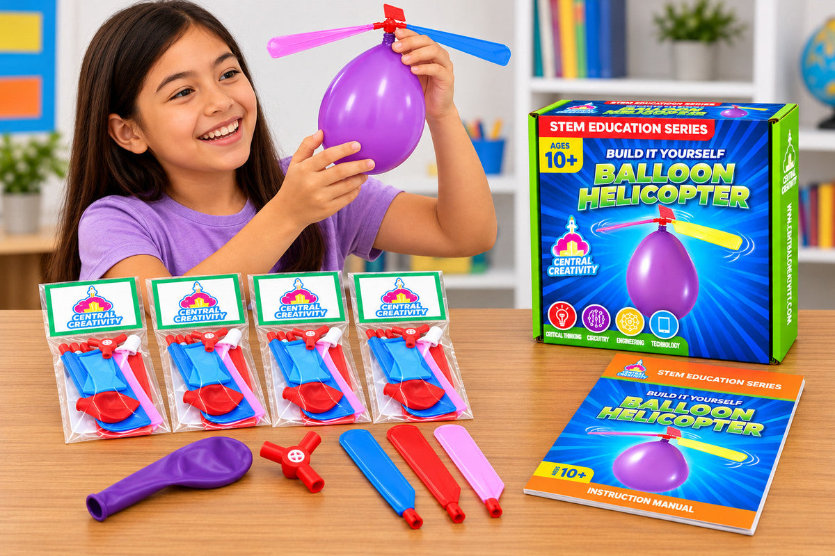 A girl holding up an assembled balloon helicopter at a classroom table, with four kits and the instruction manual in front of her