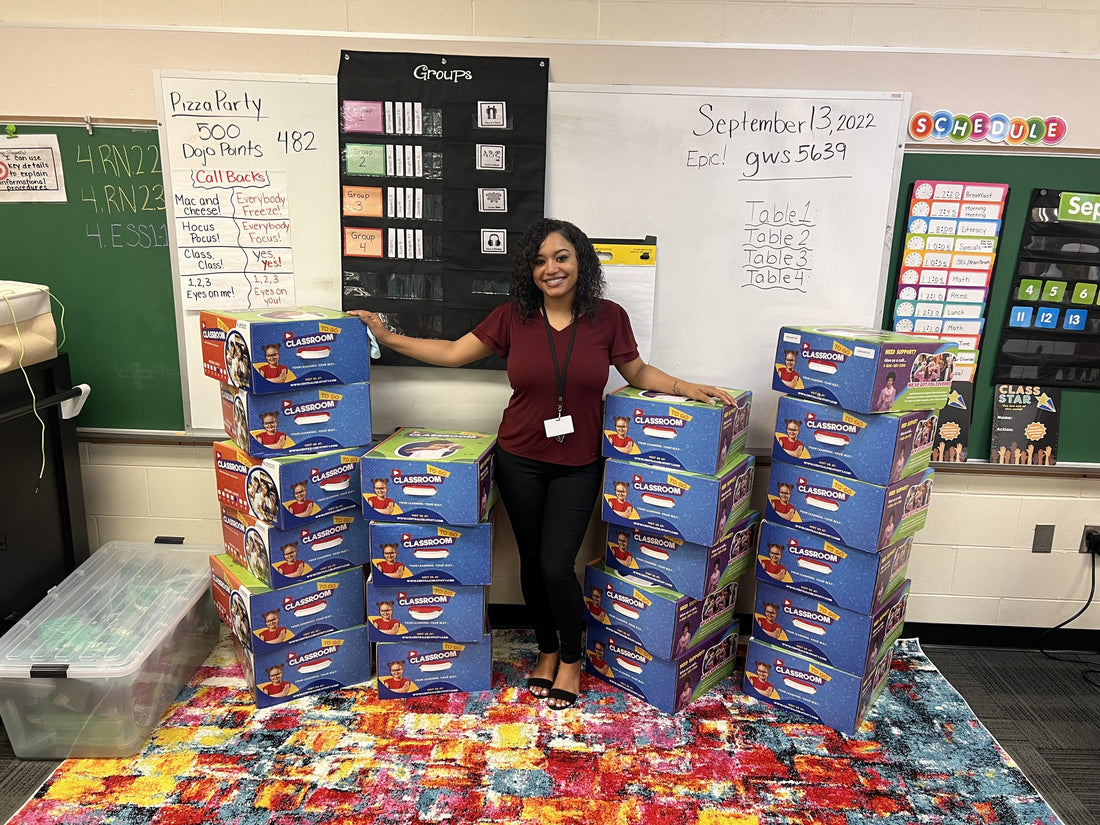 Skylar Thomas in her classroom at Muessel Elementary, standing beside stacked Classroom TO GO kit boxes