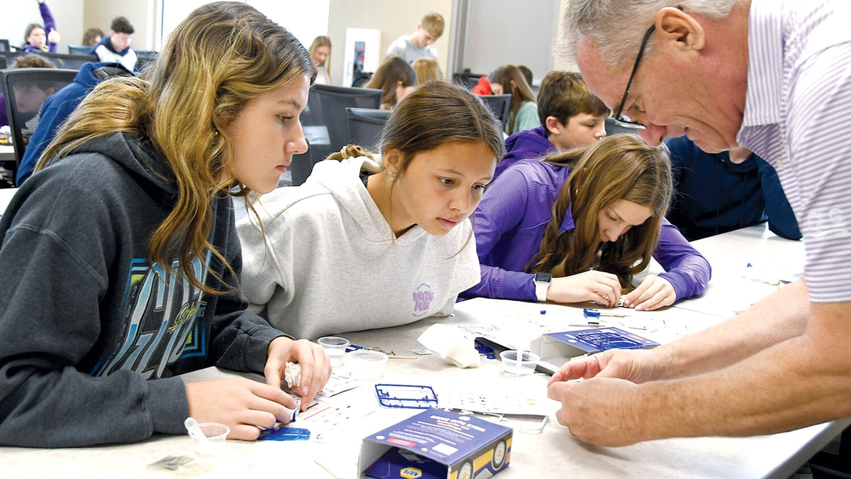 A store table mid-event: the STEM Event Today sign, a family at the build. Again, a real photograph, not the report's.
