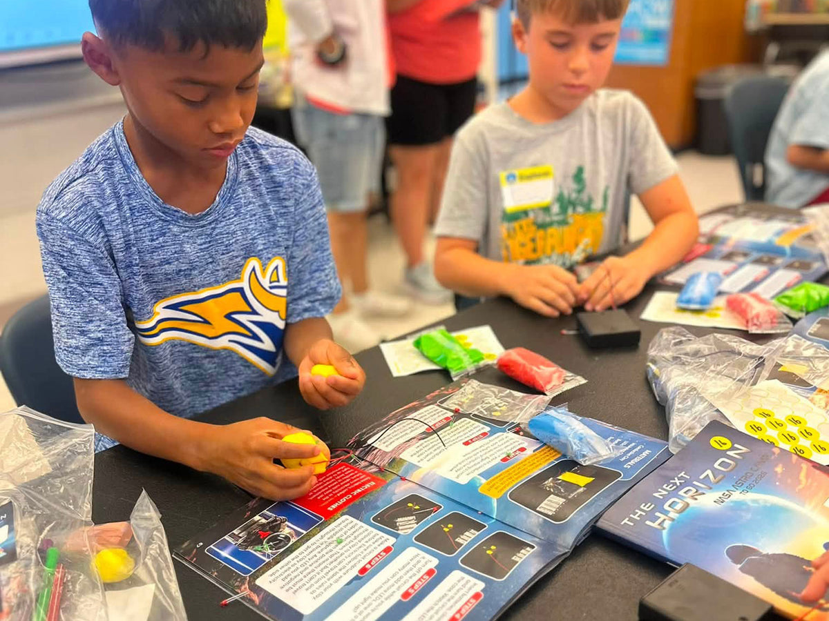 A teacher and students opening a Central Creativity kit and handing out the individually packaged activities.
