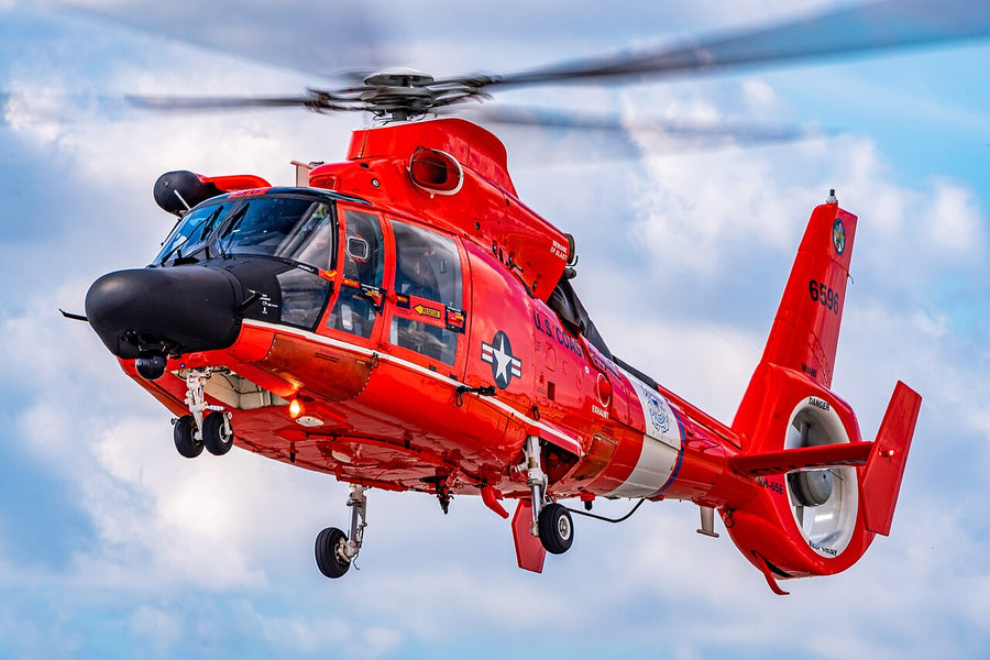 A US Coast Guard MH-65 Dolphin helicopter in flight, its main rotor blurred into a disc