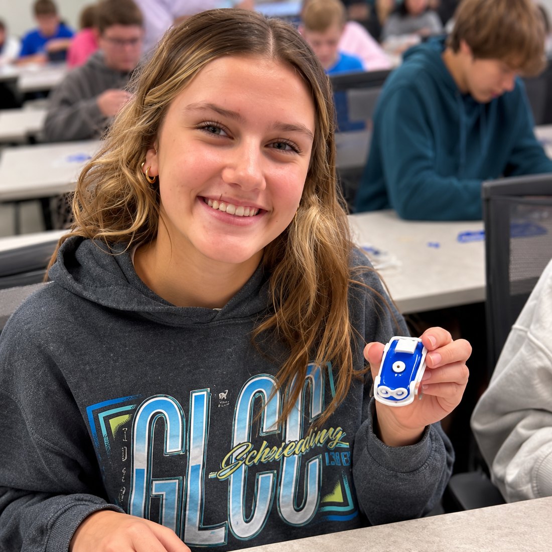 A student holding up the small blue and white saltwater car she has just finished building