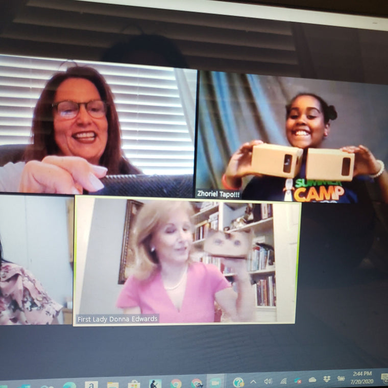 A laptop screen during a virtual event, three windows side by side: Jan Brenan laughing at top left, a Scholastic Student Reporter holding a cardboard build up to her webcam, and former Louisiana First Lady Donna Edwards holding up one of her own.