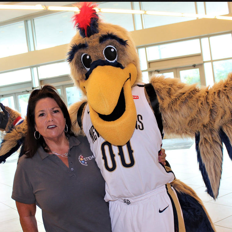 Jan Brenan laughs with her arm around the New Orleans Pelicans mascot in the team&rsquo;s STEM Zone, where she was running a STEM event with Chevron.