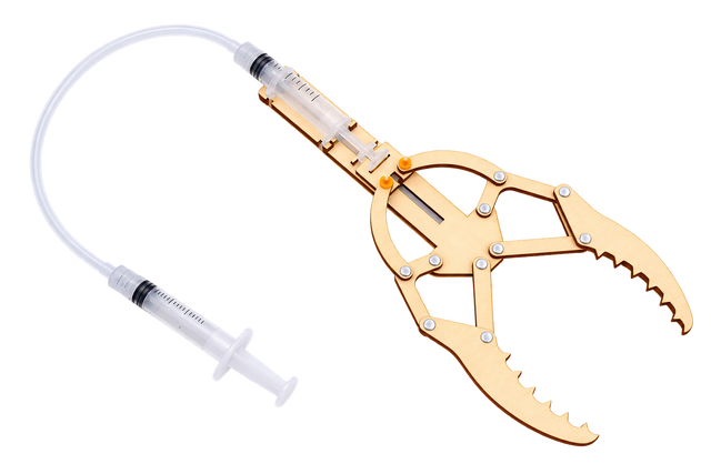 An assembled Hydraulic Gripper: two syringes joined by a clear hose, driving a wooden toothed claw
