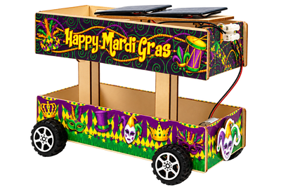 The finished float, a two-deck wooden cart on four rubber wheels, its upper deck reading Happy Mardi Gras and its lower deck wrapped in purple, green and gold jesters, masks and crowns, with two solar panels mounted on the roof and wired down to the motor.
