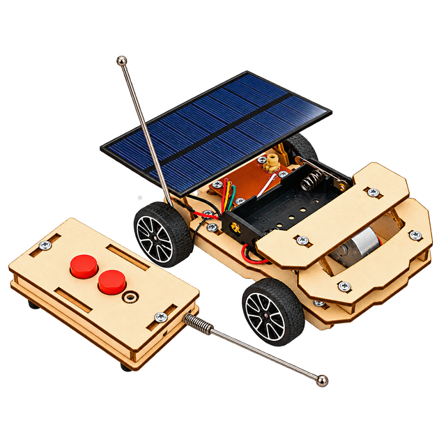 The finished solar car with its panel raised on the roof and its antenna up, beside the wooden remote control with two red buttons